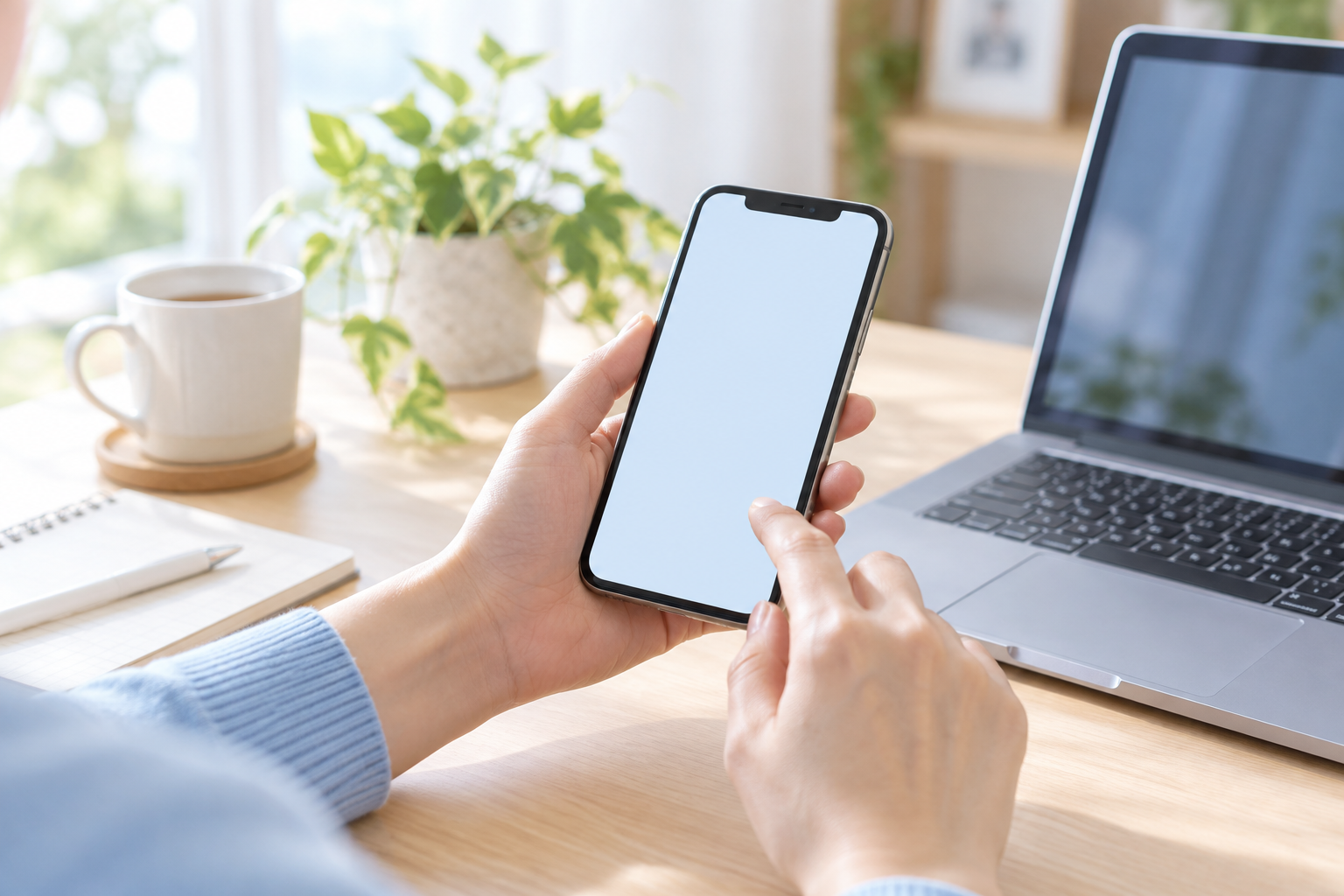 自宅のデスクでスマートフォンを確認するイメージ